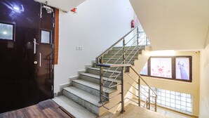 A staircase with metal railings and a dark door on the left. - Fabhotel Dwarka Suites (New Delhi)