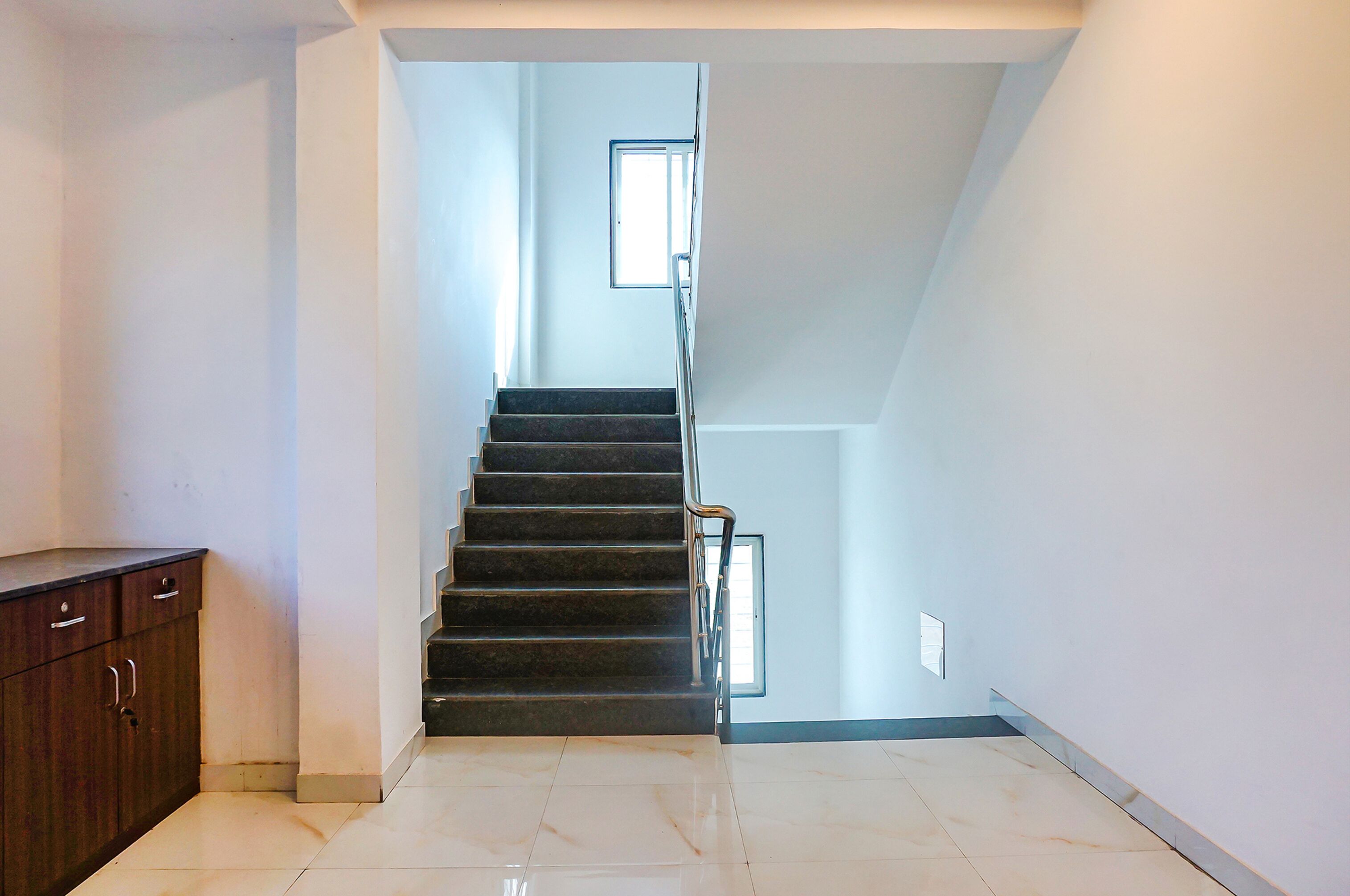 A staircase leading to an upper floor, a wooden cabinet, and a small window providing natural light.