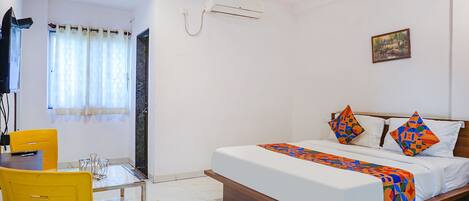 A bedroom with a bed, a desk, and a chair.