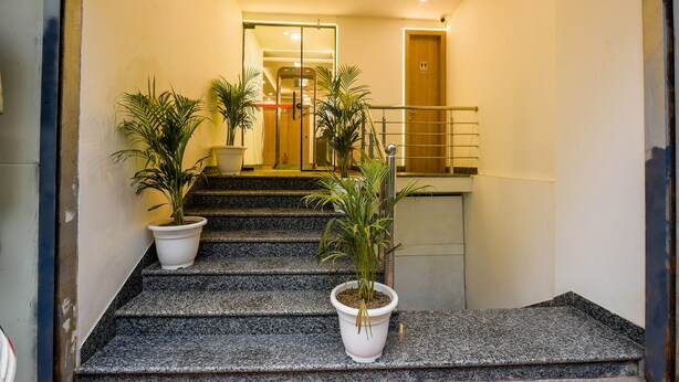 A staircase with granite steps, potted plants, and a wooden door at the top. - Fabhotel Royal Residency I (New Delhi)