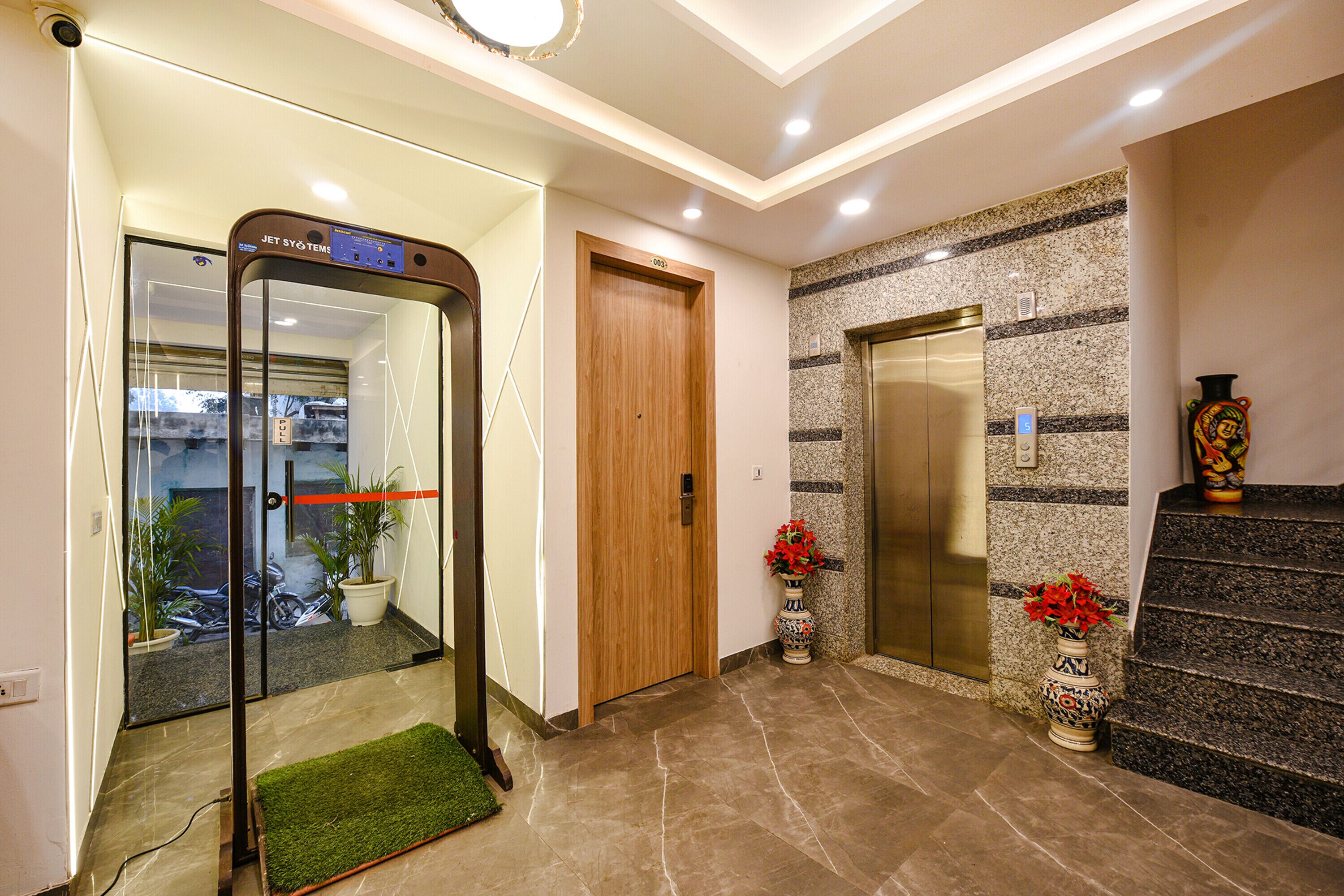 A modern elevator, a reception desk, and a potted plant in a lobby area.