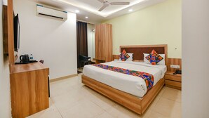 A hotel room with a bed, bedside table, nightstand, desk, chair, wardrobe, ceiling fan, air conditioning unit, and a TV. - Fabhotel Royal Residency I (New Delhi)