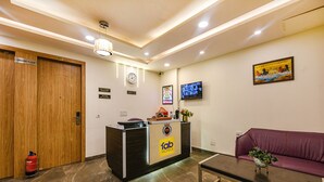 A hotel reception area with a reception desk, a clock, a television, and a sofa. - Fabhotel Royal Residency I (New Delhi)