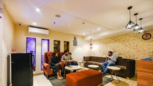 A modern lounge area with seating, a coffee table, and a television. - Fabhotel Prime Blest Park (New Delhi)