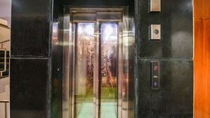 An elevator with a metallic interior, a digital control panel, and a glass door with decorative patterns. - Fabhotel Prime Blest Park (New Delhi)