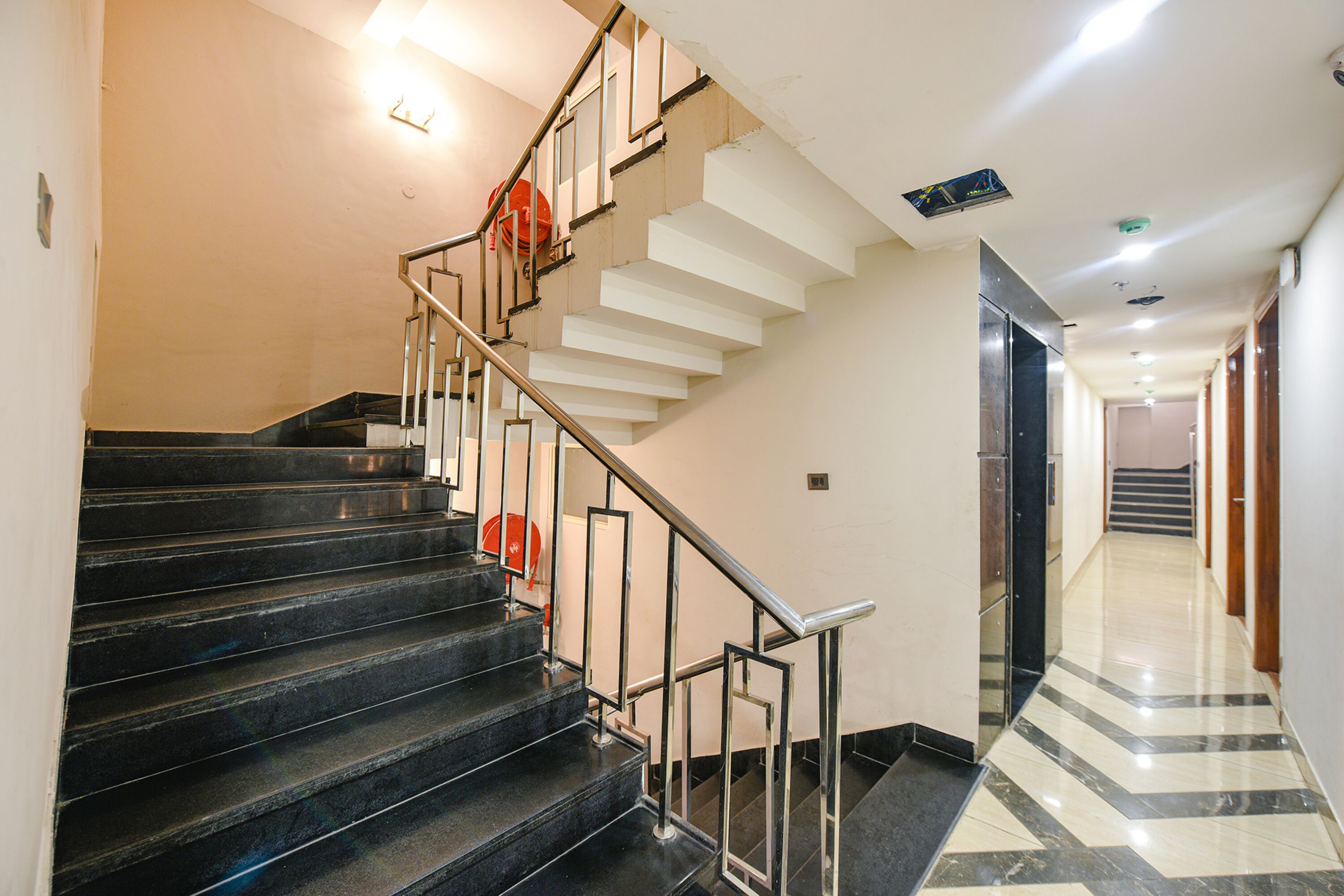 A staircase with black steps and metal railings, leading to a landing with a white wall and a door.