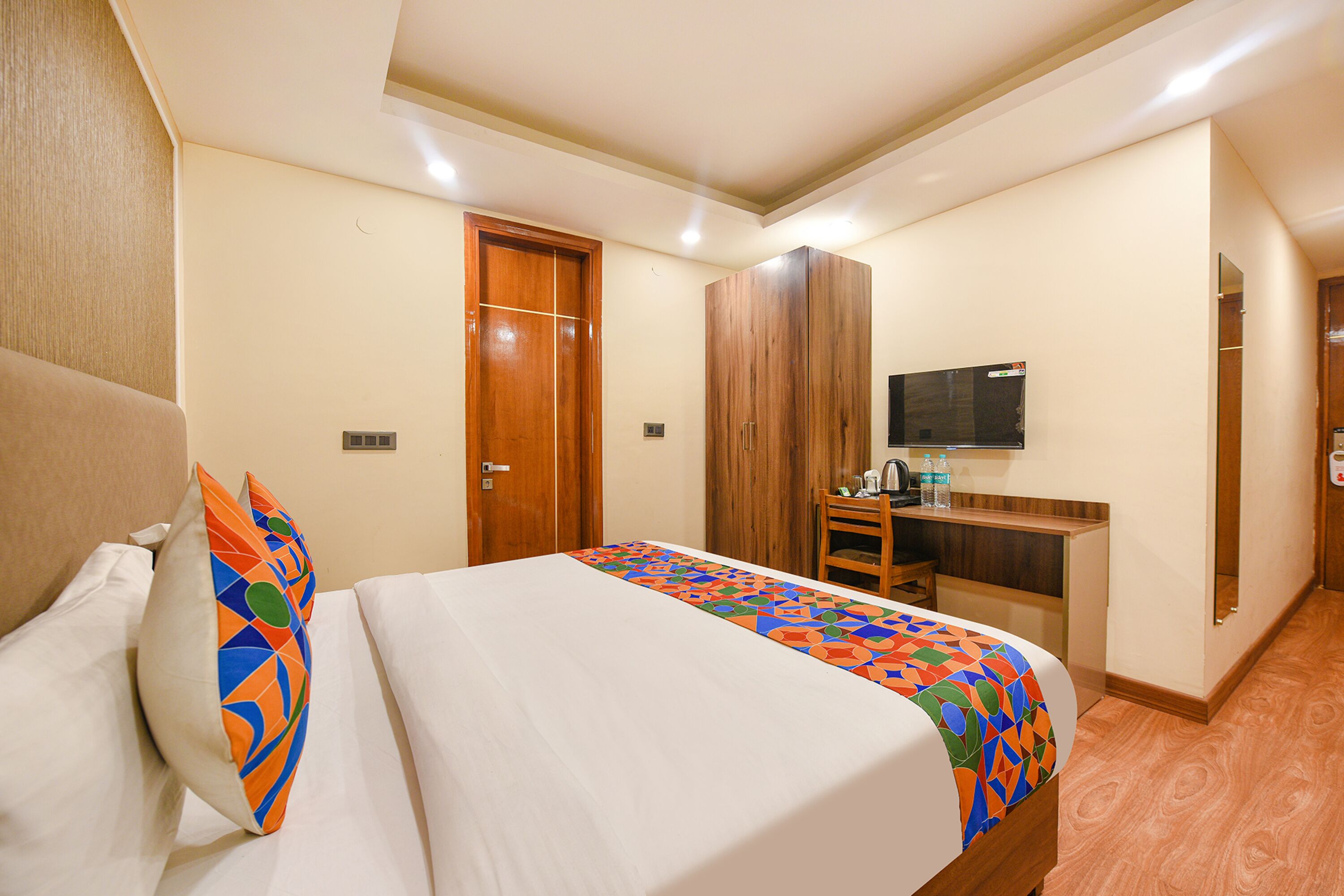 A hotel room with a bed, a desk, a television, and a wardrobe.