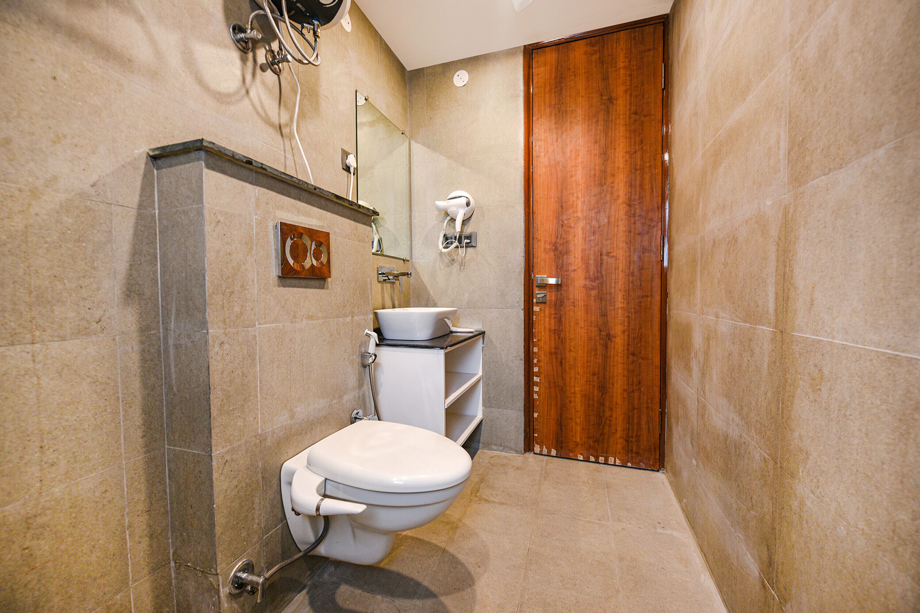 A modern bathroom with a toilet, vanity, and a wooden door.