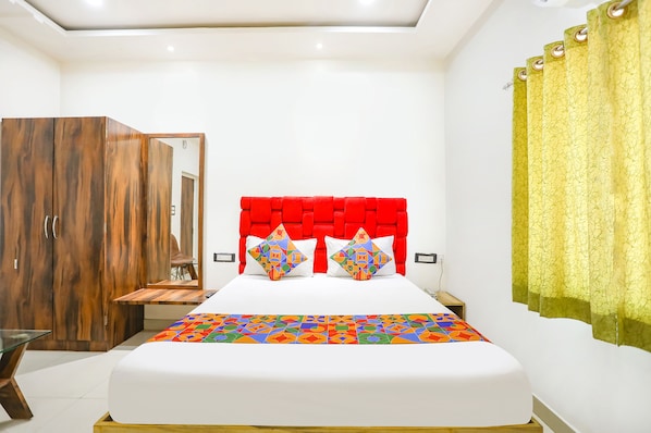 A bedroom with a bed, a wardrobe, a nightstand, and a mirror.