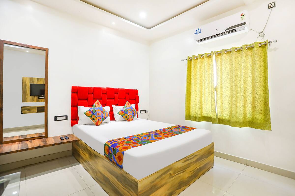 Une chambre à coucher moderne avec une tête de lit en bois, un grand lit, une table de chevet et un climatiseur fixé au mur.