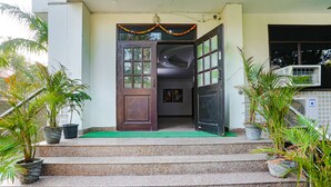 A building entrance with a wooden door, steps, and potted plants. - Fabhotel Corporate Stay (Noida)