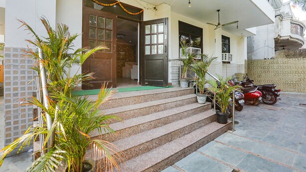A house with a porch, steps leading to the entrance, and a motorcycle parked outside. - Fabhotel Corporate Stay (Noida)