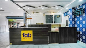 A hotel reception desk with a 'fab hotels' sign, a ceiling fan, and a patterned wall. - Fabhotel Lalitha Elite (Vijayawada)