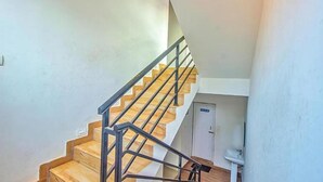 Una escalera de madera con barandas metálicas que conduce a una puerta con un letrero.
