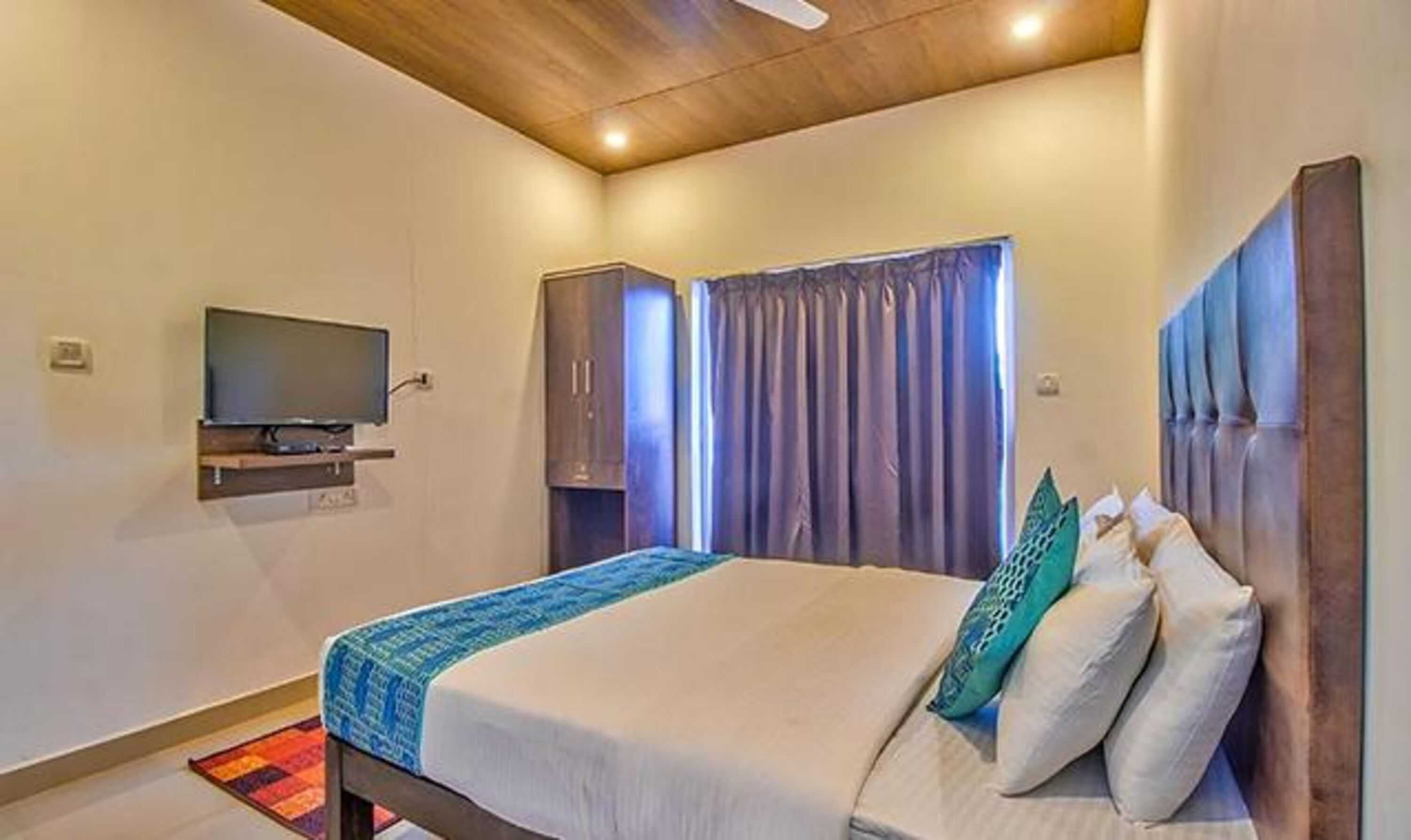 Une chambre à coucher avec un lit, une télévision et une fenêtre avec des rideaux.