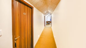 A corridor with wooden ceiling and walls, a carpeted floor, and a door with a number plate. - Fabhotel Beer Castle (Theog)