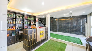 A reception area with a reception desk, shelves of beverages, and a staircase leading to upper floors. - Fabhotel Beer Castle (Theog)