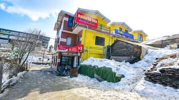 A multi-story building with a prominent red sign for Ananta Inn, a yellow building with a blue sign for Toh Hotels, and a staircase leading to the upper floors.