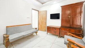 A room with a sofa, a wooden cabinet, and a television on the wall. - Fabhotel Beer Castle (Theog)