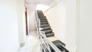 A staircase with a metal handrail, white walls, and a tiled floor. - Fabhotel Beer Castle (Theog)