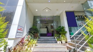 A hotel entrance with a staircase, glass doors, and potted plants. - FabHotel Upstream Sarjapur (Bengaluru)