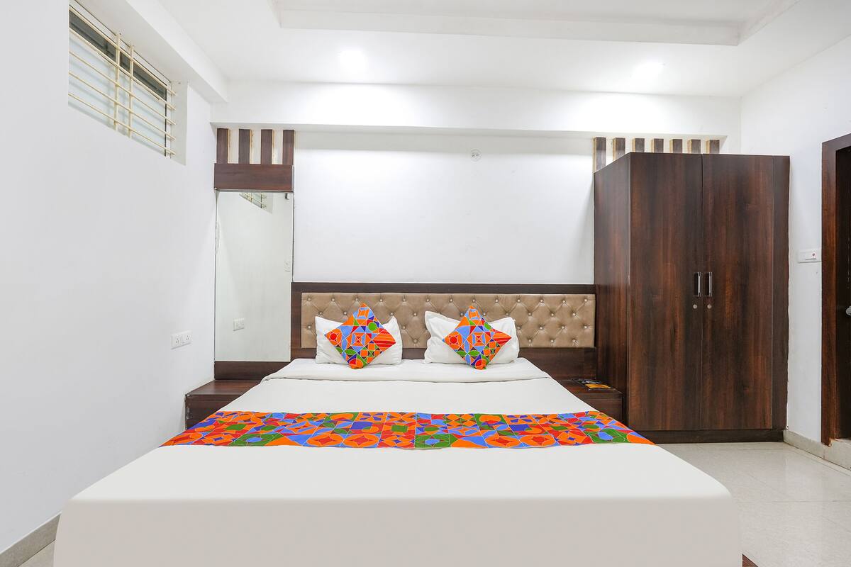 A bedroom with a bed, nightstands, a wardrobe, and a window with blinds.