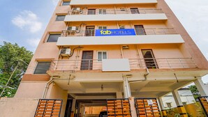 Un hotel de varios pisos con un llamativo letrero de 'fab hotels', balcones y una entrada con portón.