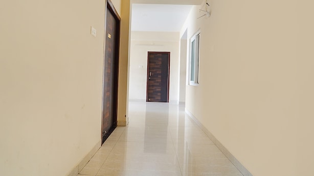 Un pasillo con suelo de baldosas, una puerta de madera y una ventana a la derecha.