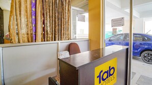 Un mostrador de recepción con un letrero que dice 'Tab Hotels' y una vista de un coche azul afuera.