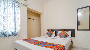 Una cama bien hecha con una colcha colorida, un cabecero y dos almohadas decorativas.