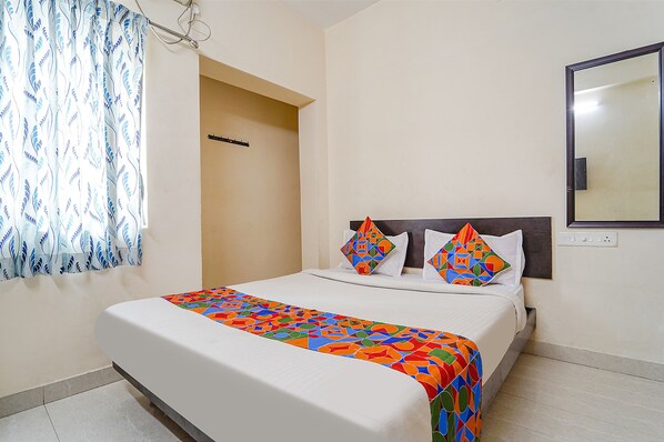 A neatly made bed with a colorful bedspread, a headboard, and two decorative pillows. - Fabexpress Vangal Nest (Coimbatore)
