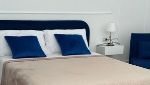 Un lit recouvert d’une courtepointe beige, doté d’une tête de lit bleu foncé et de coussins assortis de la même couleur.