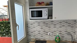 Une cuisine compacte équipée d’un four à micro-ondes, d’un évier et d’un petit plan de travail.