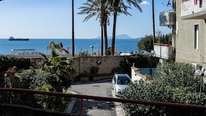A coastal residential area with a view of the sea, palm trees, and a parked car. - Rua de Mar Portici (Portici)