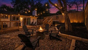 A backyard with a fire pit, outdoor seating, and string lights. - Barton Hills Hideaway + Hot Tub - Magdalena 1! (Austin)