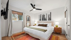 A neatly arranged bedroom with a bed, bedside tables, a ceiling fan, and artwork on the walls. - Barton Hills Hideaway + Hot Tub - Magdalena 1! (Austin)