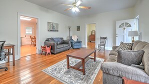 A spacious living room with hardwood flooring, a ceiling fan, and a large window. - Walter & Mae's Farmhouse: Charming accomodations with gorgeous mountain views (Elizabethton)