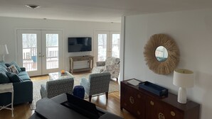 Ein Wohnzimmer mit Fernseher, Sofa, Sesseln und Couchtisch.