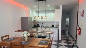 Een moderne keuken met witte kastjes, een centraal eiland en hangende lampen.