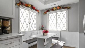 Una cocina moderna con armarios blancos, encimera de mármol y una isla central con asientos.