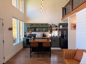 A modern kitchen with green cabinets, a central island, and a dining area with a table and chairs.