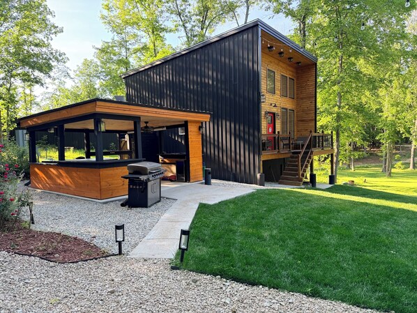 A modern two-story house with a covered outdoor kitchen and a deck.