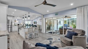 Un vaste espace de vie comprenant un canapé, une table basse et donnant sur la cuisine et la terrasse.