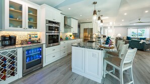 Une cuisine moderne avec des meubles blancs, des appareils en acier inoxydable et un îlot central doté de sièges.