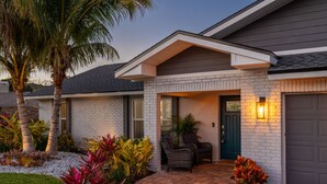 Une maison moderne avec une façade en briques, une véranda couverte avec des chaises et un garage.