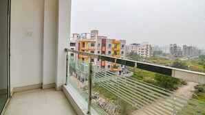 A balcony with a metal railing overlooking a residential area with colorful buildings. - Fabhotel White House I (Kolkata)