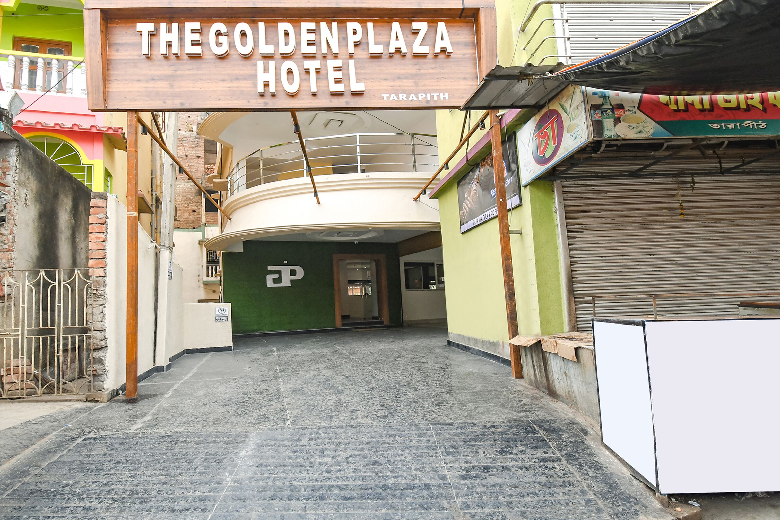 L'entrée de l'hôtel Golden Plaza à Tarapith se distingue par une enseigne bien visible, une grille et un escalier menant à l'étage supérieur.