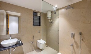 Un baño con mampara de vidrio, un lavamanos blanco, un inodoro y una zona de ducha.
