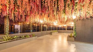 An indoor space with a polished concrete floor, large windows, and hanging floral decorations. - Fabhotel Prime Opulence (Chhatrapati Sambhajinagar)
