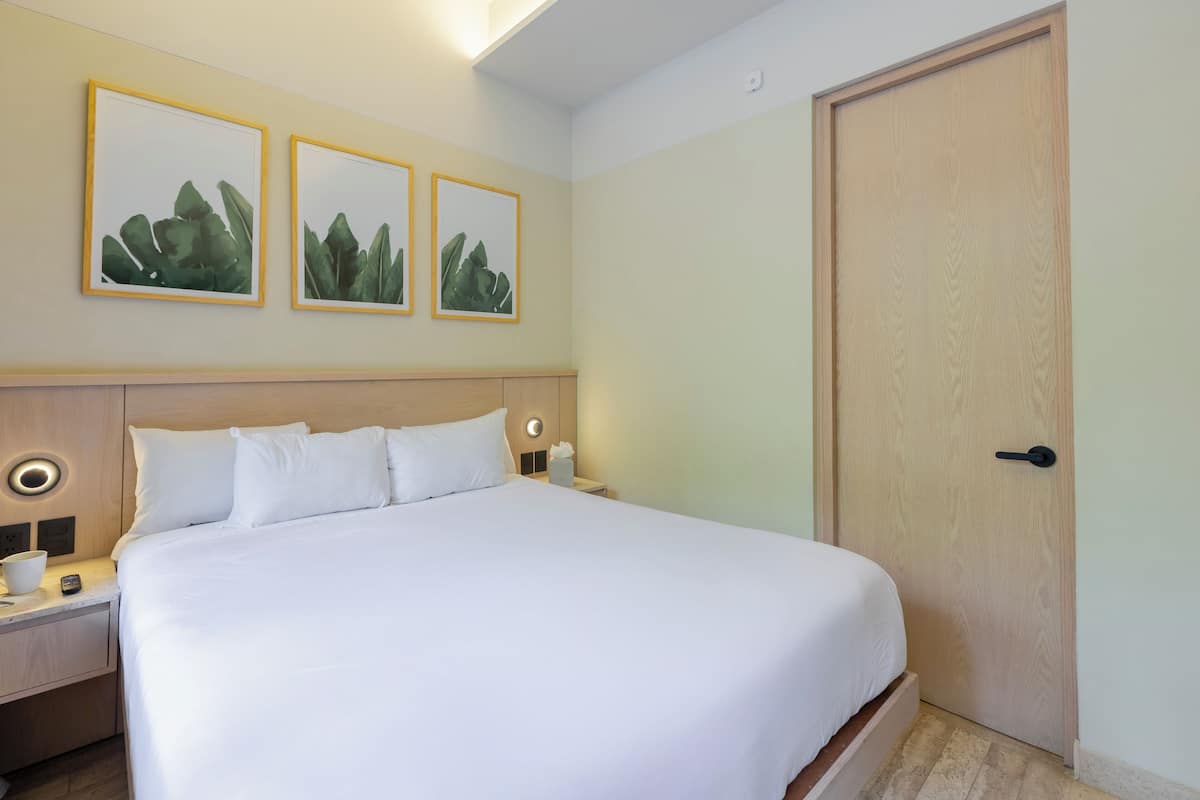 A neatly made bed with white linens, a wooden headboard, and bedside tables with lamps. There are three framed pictures on the wall above the bed.